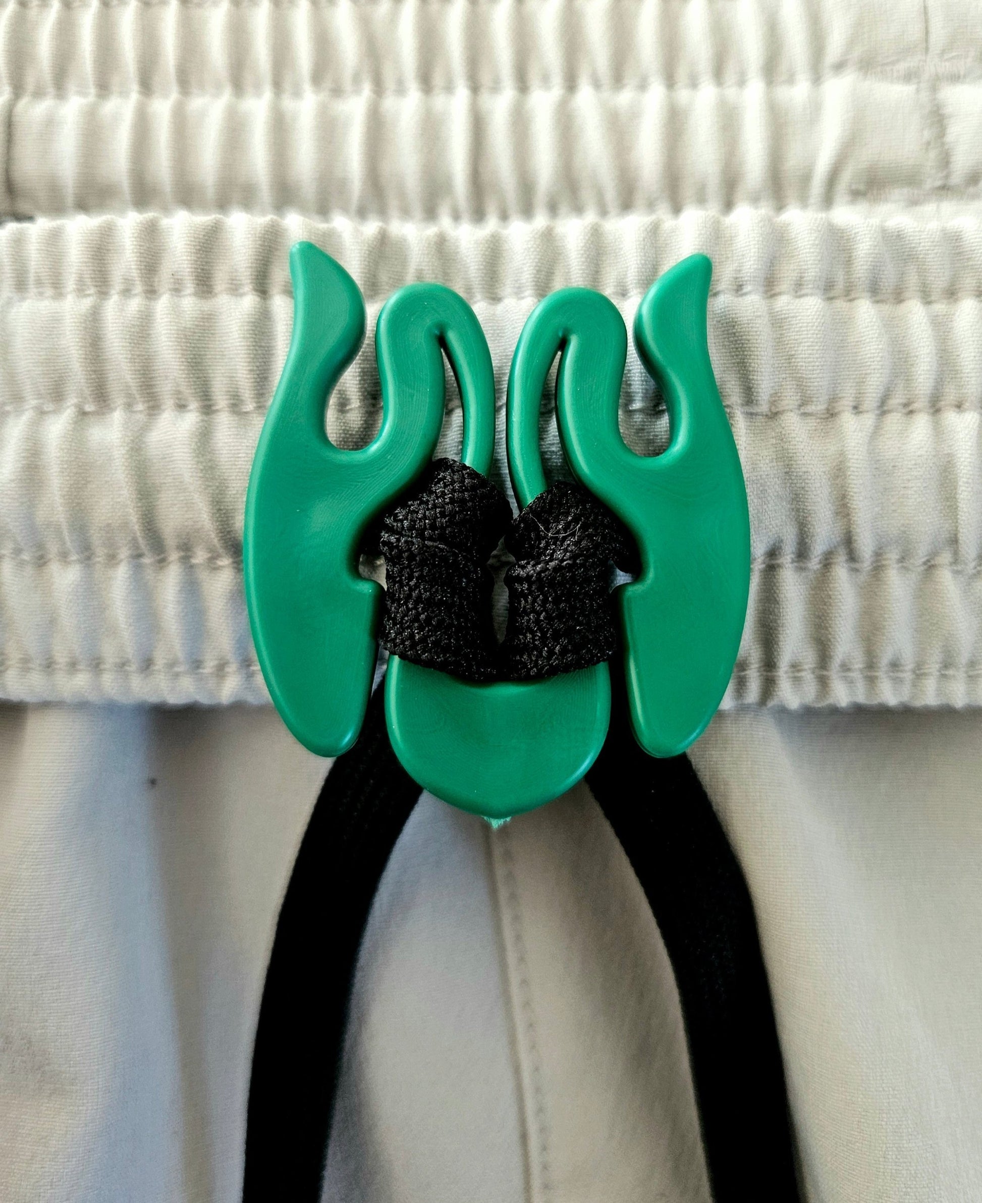 Close up picture demonstration  of Wiggley, a tool that keeps clothing drawstrings from getting lost in the washer.